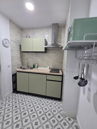a small kitchen with white cabinets and a tile floor at Las Casitas de Jisa in Talavera de la Reina