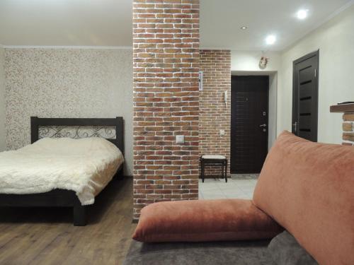 a bedroom with a bed and a brick wall at Academic apartment in Vinnytsya