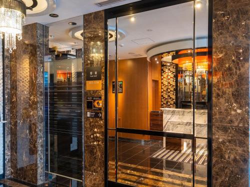 a lobby with glass doors and a chandelier at APA Hotel Nagoya Sakae Higashi in Nagoya