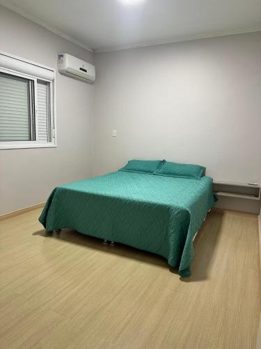 ein Schlafzimmer mit einem grünen Bett in einem weißen Zimmer in der Unterkunft Ap Independecia in Santa Cruz do Sul