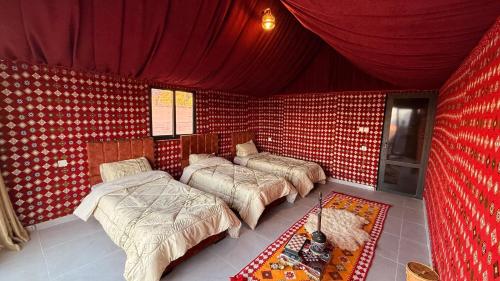 a room with three beds in a red room at Bedouin Nature Camp in Wadi Rum