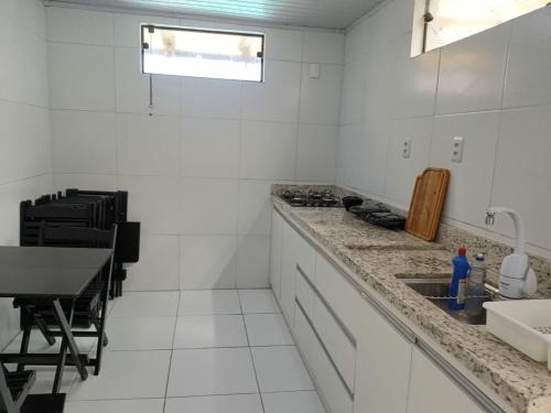 a white kitchen with a sink and a table at The Guest House pousada e hostel in Balneário Gaivotas