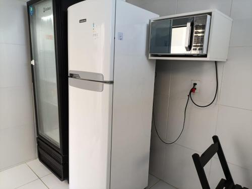 a white refrigerator with a microwave on top of it at The Guest House pousada e hostel in Balneário Gaivotas