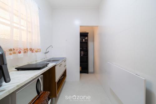 a white kitchen with a sink and a stove at Aptos completos com localização privilegiada no coração de Floripa – CSNs in Florianópolis
