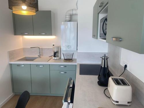 une cuisine avec des placards bleus et un grille-pain dans l'établissement Entre Sable et Océan, appartement avec vue mer, à Fort-Mahon-Plage