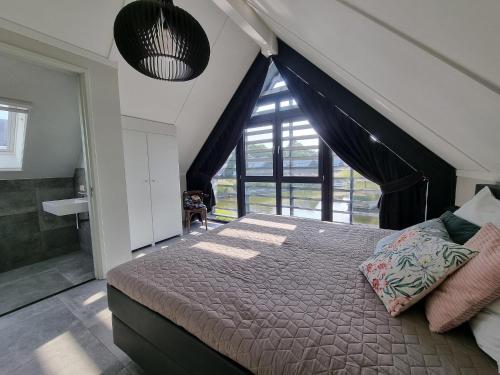 ein Schlafzimmer mit einem Bett und einem großen Fenster in der Unterkunft Water Villa in Balk with Private Jetty in Balk