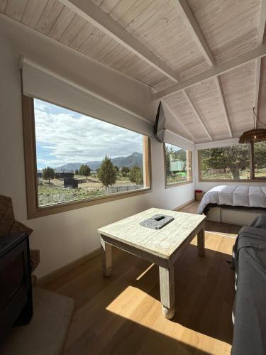 a living room with a table and a large window at Cabaña El galpon - Villa Meliquina de Espacio Bandurrias - in Villa Meliquina