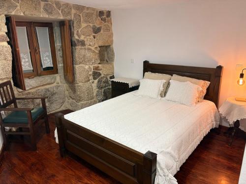 a bedroom with a bed and a stone wall at Sidrós Houses in Vila Nova