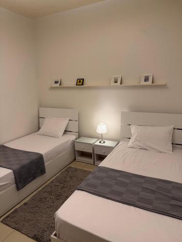 a bedroom with two beds and a lamp on a table at Entire Apartment with Garden in Sheikh Zayed