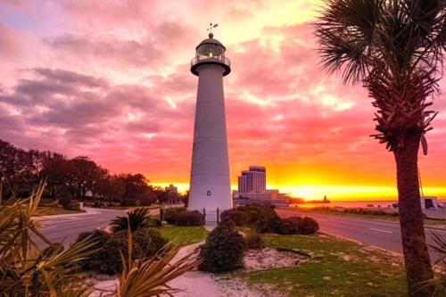 a lighthouse with a sunset in the background at Royal Holiday Beach Resort in Biloxi