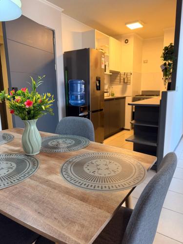 Una cocina con una mesa con un jarrón de flores encima. en Departamento rancagua centro nuevo, en Rancagua