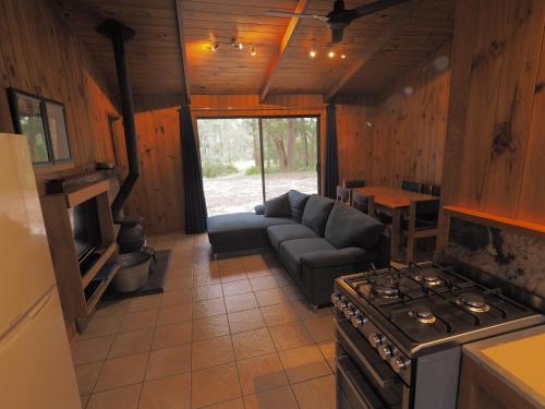 a living room with a couch and a stove at Bournda Cabins at Woodbine in Bournda Island