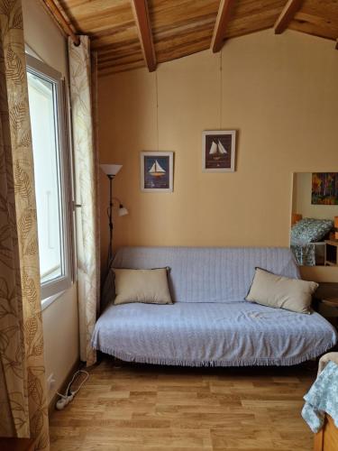 a bed sitting in a room with a window at Сocon bien douillet in Saint-Denis-dʼOléron
