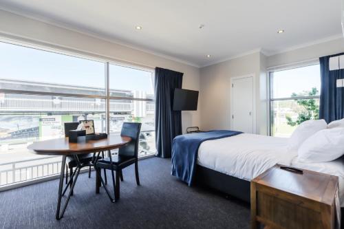 a hotel room with a bed and a table and a window at Hamilton Suites in Hamilton