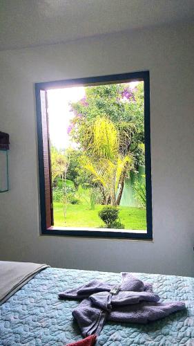 a bedroom with a window with a blanket on a bed at Chales das Andorinhas in Lavras Novas