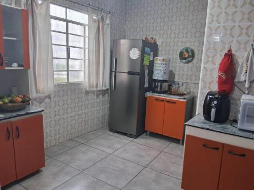 a kitchen with a stainless steel refrigerator and orange cabinets at Hostel Mi Casa Su Casa 1 in Poços de Caldas
