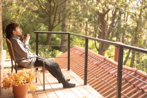 Ein Mann sitzt auf einem Stuhl auf einem Deck in der Unterkunft San José del Pacífico- Cabañas Camino al Cielo 2 in San Mateo Río Hondo