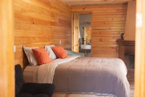 ein Schlafzimmer mit einem Bett in einer Holzwand in der Unterkunft San José del Pacífico- Cabañas Camino al Cielo 2 in San Mateo Río Hondo