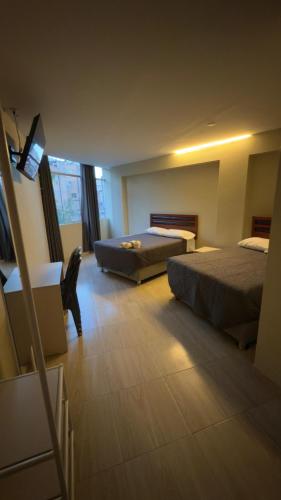 阿亚库乔Hotel Rodilla的有两张床和一张书桌的酒店房间