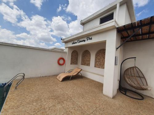 a white building with a chair on a patio at Cozy Apartment, 2 bedrooms, 2 bathrooms, Rooftop swimming, Full packed GYM, and workplaces in the Heart of Westlands, Nairobi in Nairobi