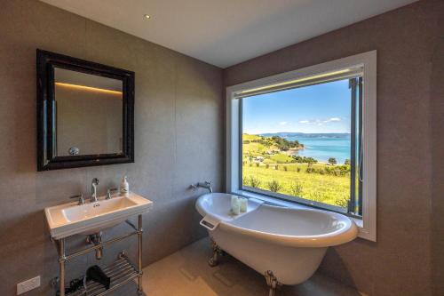 uma casa de banho com uma banheira, um lavatório e uma janela em The Keep at Woodside Bay em Waiheke Island