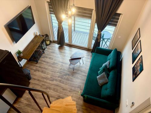 a living room with a green couch and some windows at Vista - Domek Wakacyjny w Górach Sowich in Sierpnica