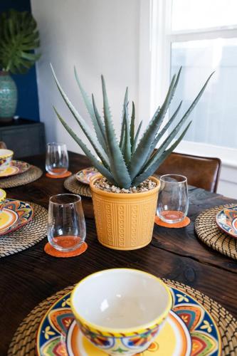 a table with plates and a potted plant on it at * Bueno Bueno Casita * / 7 min to Downtown / 4 Bdr in San Diego