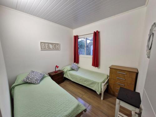 a bedroom with two beds and a dresser and a window at Hermosa casa a estrenar en Playa Grande ELIXIR in San Gregorio de Polanco