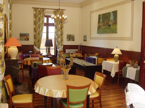 een eetkamer met tafels en stoelen en een kroonluchter bij Castel de la Pique in Luchon