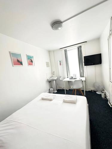 a white bedroom with a bed and a desk at Number 75 in Brighton & Hove