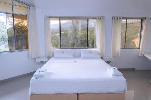 Schlafzimmer mit einem großen weißen Bett und Fenstern in der Unterkunft Hotel Real Park in Tarapoto