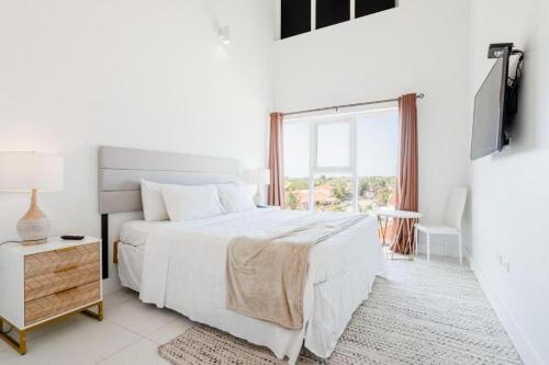 a white bedroom with a bed and a window at Arubas Life 303 in Noord