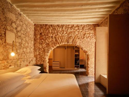 a bedroom with a bed and a stone wall at Hotel Sevilla in Mérida