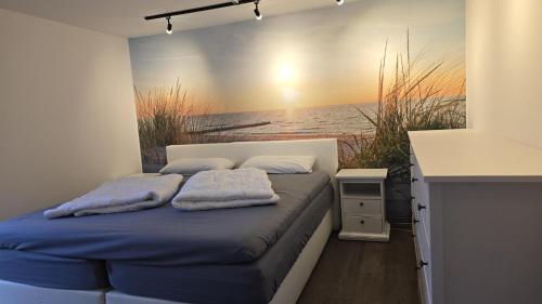 a bed in a room with a painting of the ocean at Ferienhaus Klippenbarsch in Dornum
