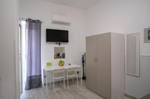 a white dining room with a table and a tv on a wall at L'angolo del viaggiatore in Nicosia