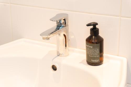 une bouteille de savon posée sur un lavabo de salle de bain dans l'établissement Modernes Apartment in der Innenstadt Klagenfurt, à Klagenfurt am Wörthersee
