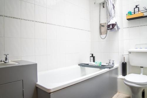 Un baño blanco con inodoro y lavabo. en Beautiful new build studio in London, en Sutton