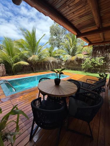 una terraza de madera con mesa, sillas y piscina en Corumbau Bangalôs, en Prado
