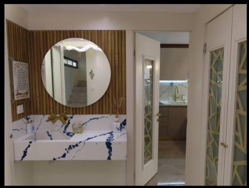 ein Badezimmer mit großem Spiegel und Waschbecken in der Unterkunft Stunning house in romema jerusalem in Gedera