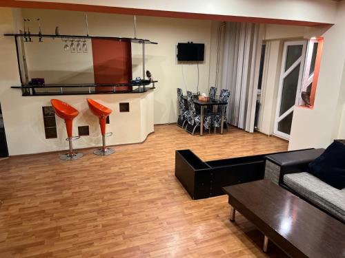 een woonkamer met een bank en oranje stoelen bij Central Home Apartment in Craiova