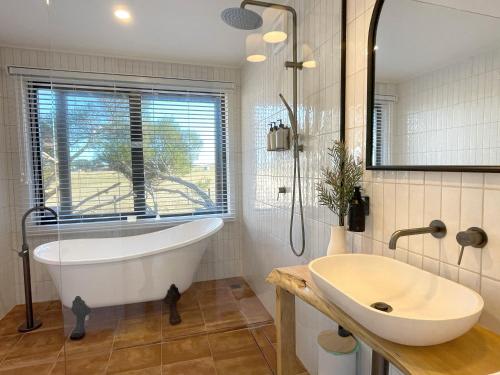 un bagno con vasca, lavandino e finestra di Phillip Island Coastal Cabins a Sunderland Bay