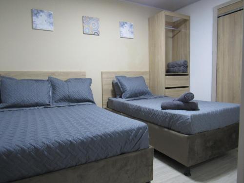 a bedroom with two beds with blue pillows at Lux Al Wafa in Bogotá