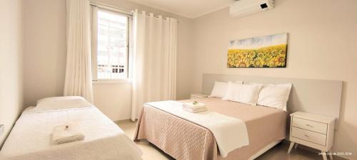 apto 4 quartos 50 metros da praia في باليريو كامبوريو: غرفة نوم صغيرة بسريرين ونافذة