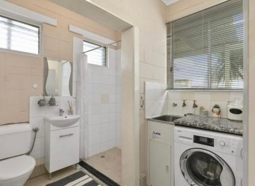 a bathroom with a washing machine and a sink at Cosy cottage at Coronet Bay in Coronet Bay