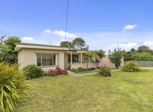 a house in a yard with a grass yard at Cosy cottage at Coronet Bay in Coronet Bay