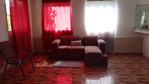- un salon avec un canapé et des rideaux rouges dans l'établissement Hospedaje Herradura de Rivas, à Rivas