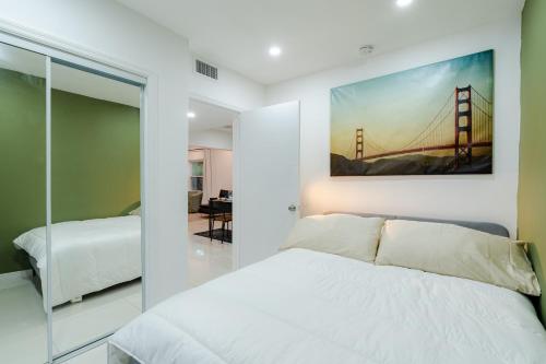 a bedroom with a white bed and a bridge painting on the wall at Beautiful, fully furnished 2bed 1bath house - 5 minute walk to Miracle Mile Downtown Coral Gables in Miami