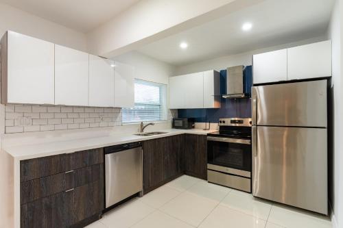 a kitchen with wooden cabinets and stainless steel appliances at Beautiful, fully furnished 2bed 1bath house - 5 minute walk to Miracle Mile Downtown Coral Gables in Miami