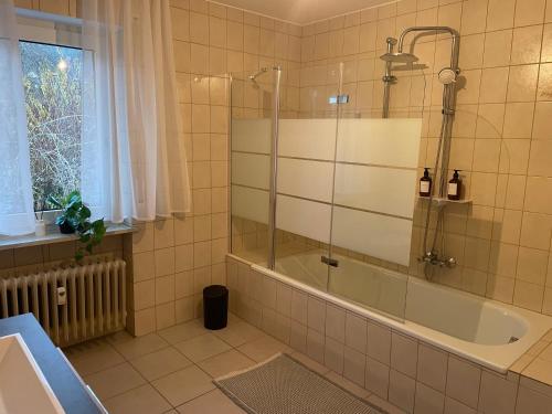 ein Bad mit einer Dusche, einer Badewanne und einem Fenster in der Unterkunft Ferienwohnung Müller - Arberblick in Lohberg