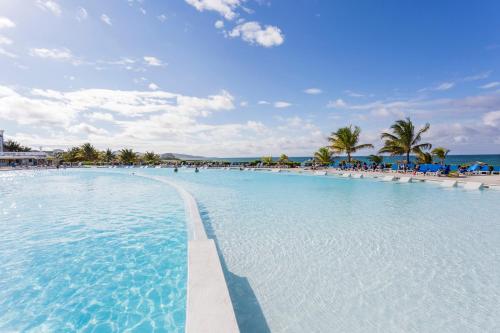 a large swimming pool with chairs and the ocean at Grand Palladium Jamaica Resort & Spa All Inclusive in Lucea
